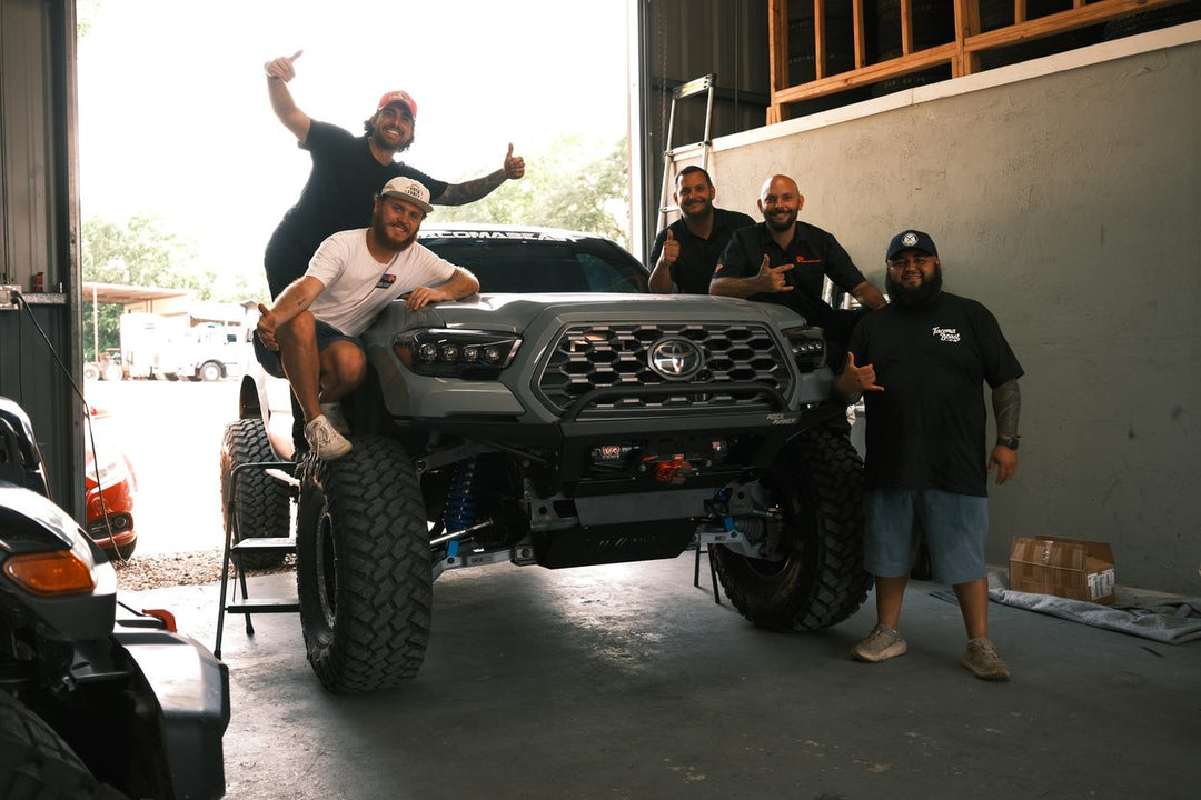 The TacomaBeast team celebrating with Ewok's finished 2021 Toyota Tacoma long travel dream build