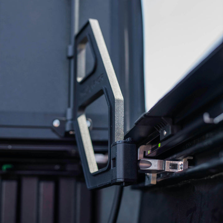 Detailed view of the TruxArmor QuadAxis Pro hard folding bed cover hinge and adjustable metal mounting bracket.